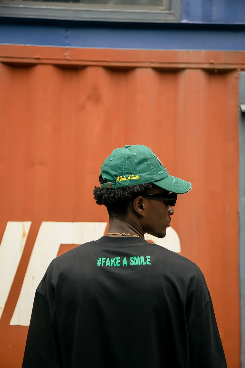 Close-up of a FakeSmile curved-brim cap with the globe patch and embroidered tagline