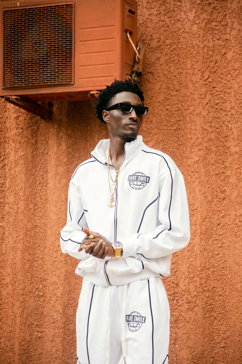 Model in a FakeSmile tracksuit leaning on a brick wall — premium streetwear made in Lagos